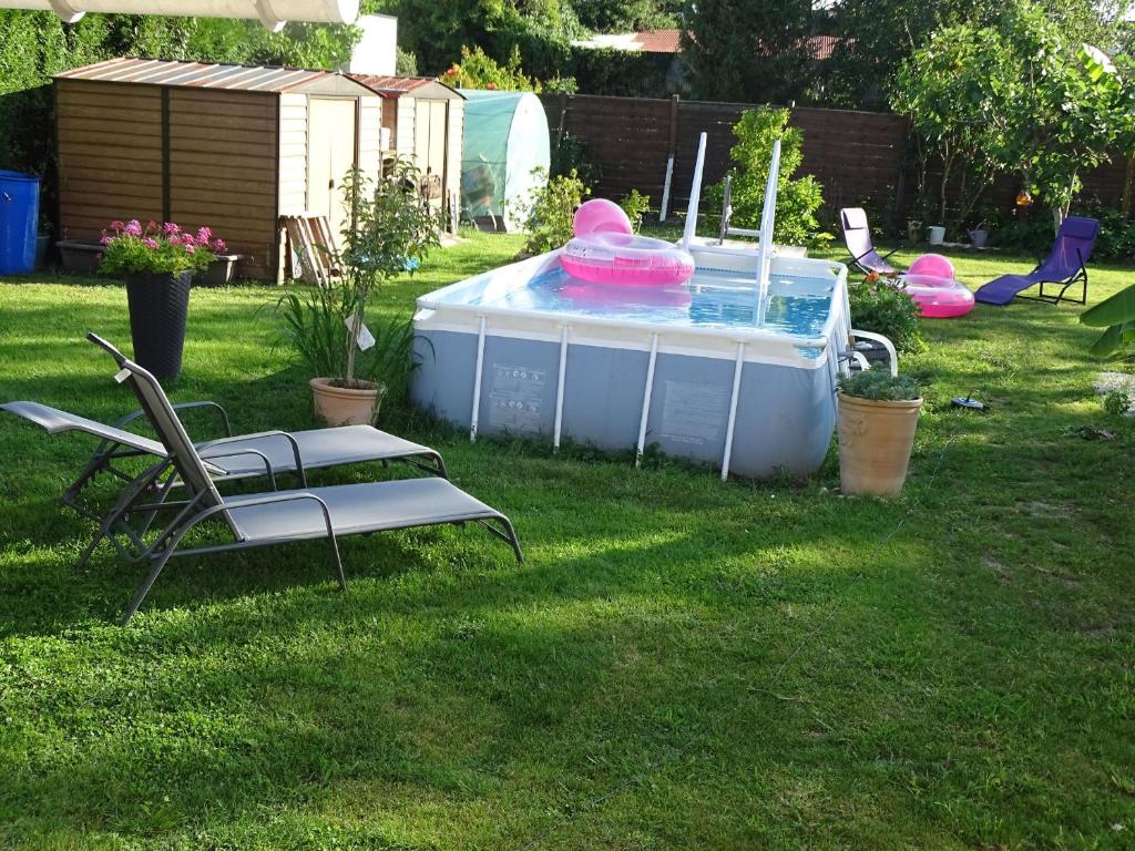 a pool in a yard with two chairs and a table at LA DATCHA in Saujon