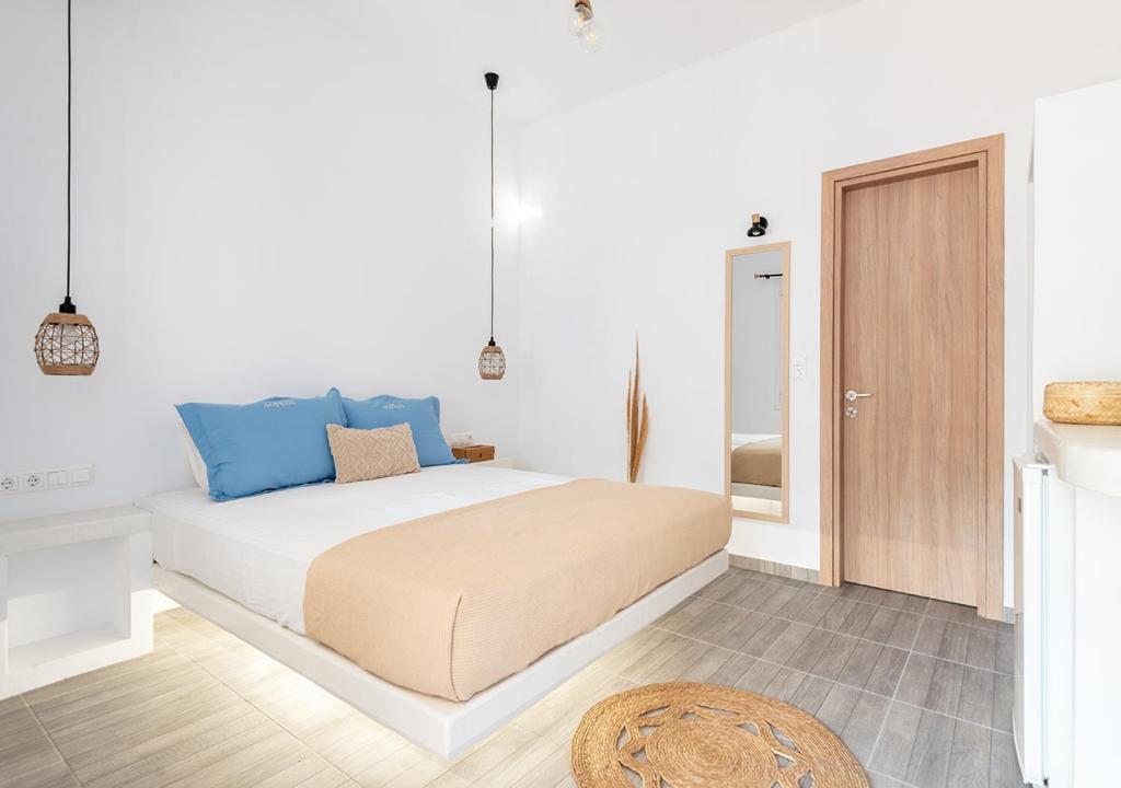 a white bedroom with a bed with blue accents at Dorkas Luxury Rooms&Apartments in Livadakia