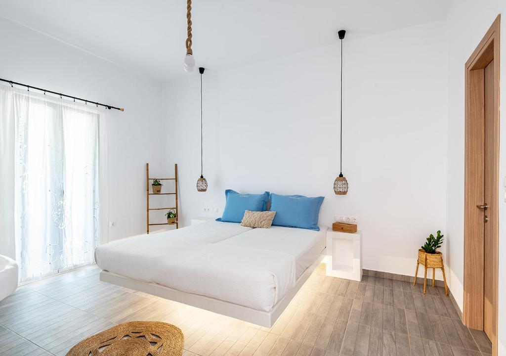a white bedroom with a large bed with blue pillows at Dorkas Luxury Rooms&Apartments in Livadakia