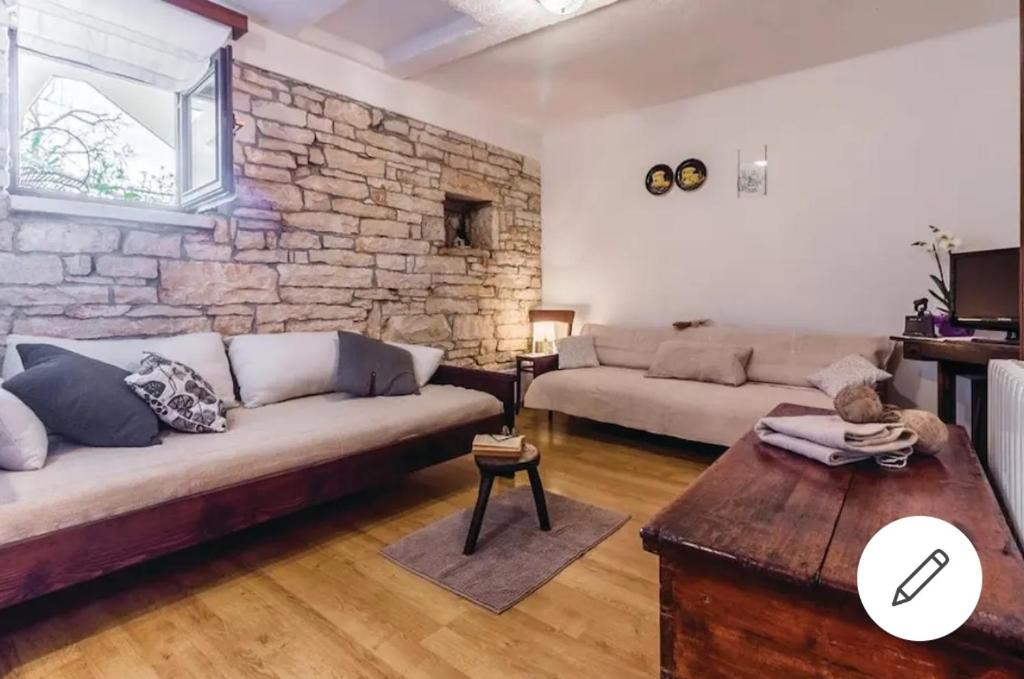 una sala de estar con 2 sofás y una pared de piedra. en Little App - magical surrounding en Sveti Petar u Šumi