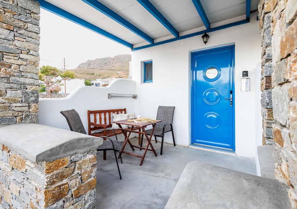 a patio with a blue door and a table and chairs at Dorkas Luxury Rooms&Apartments in Livadakia