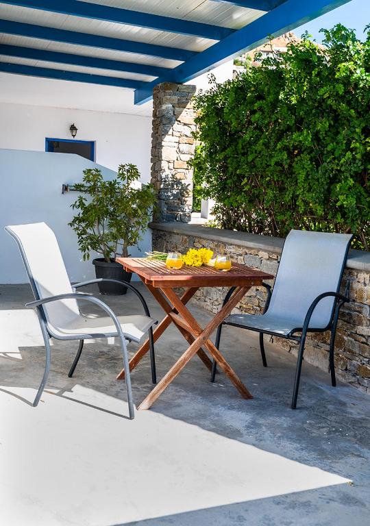 two chairs and a wooden table on a patio at Dorkas Luxury Rooms&Apartments in Livadakia