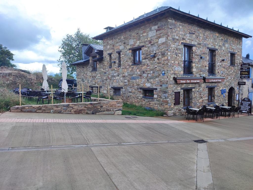 um edifício de pedra com mesas e cadeiras em frente em La Posada del Druida em Foncebadón