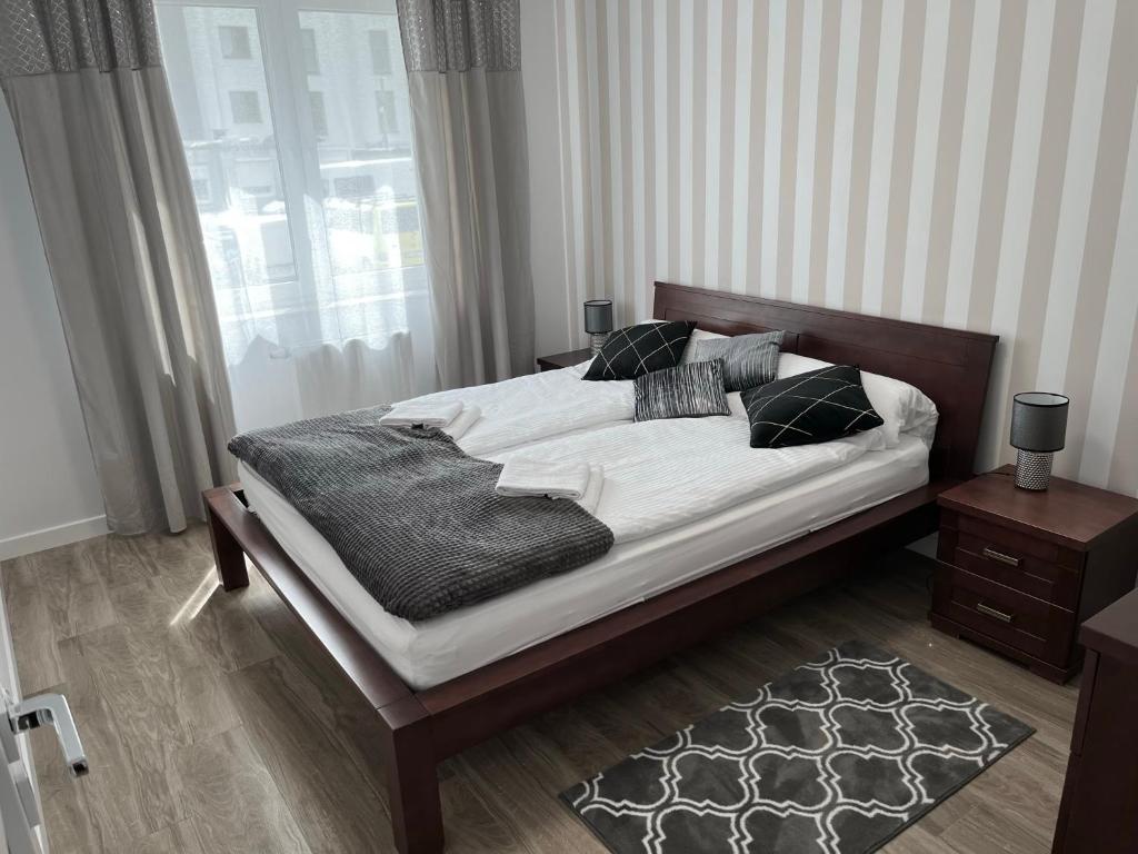 een slaapkamer met een groot bed met witte lakens en kussens bij Apartament KINGA nad rzeką Iławką in Iława