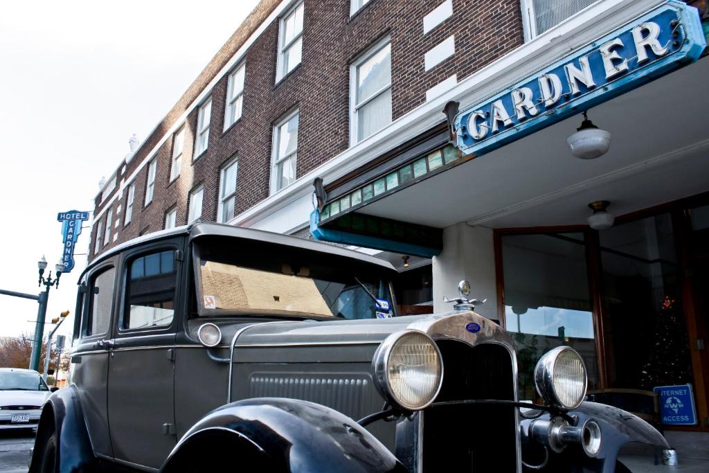 een oude auto geparkeerd voor een gebouw bij Gardner Hotel & Hostel in El Paso