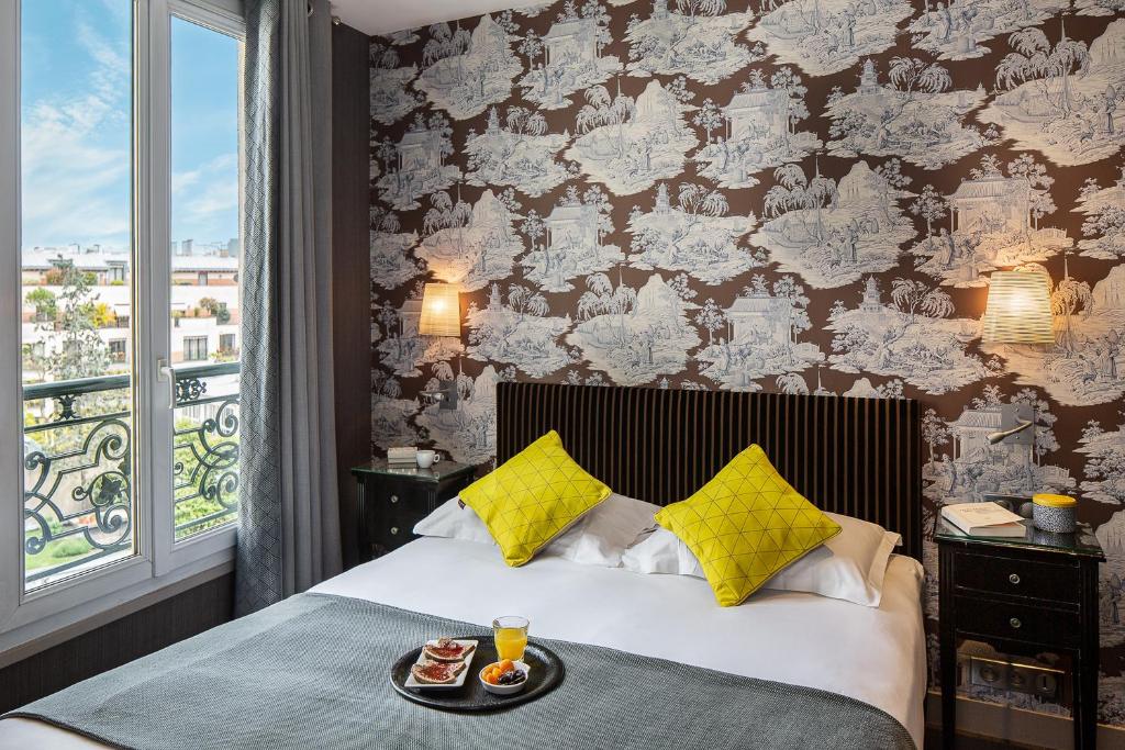 a bedroom with a bed with a tray of food on it at Hotel Louison in Paris