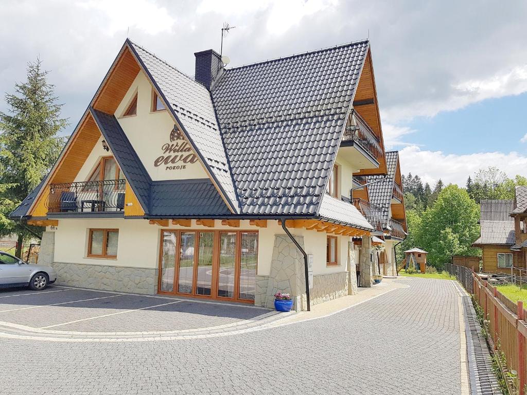 a building with a black roof on a street at Willa Ewa in Poronin