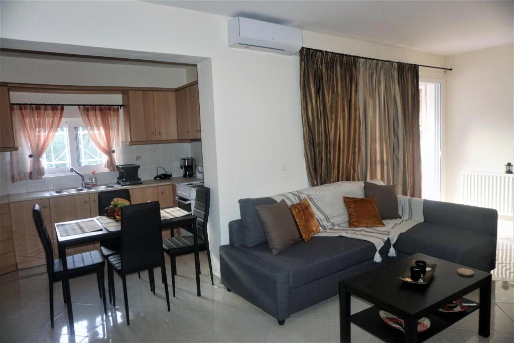 ein Wohnzimmer mit einem Sofa und einem Tisch sowie eine Küche in der Unterkunft Lasithiotakis Apartments in Póros