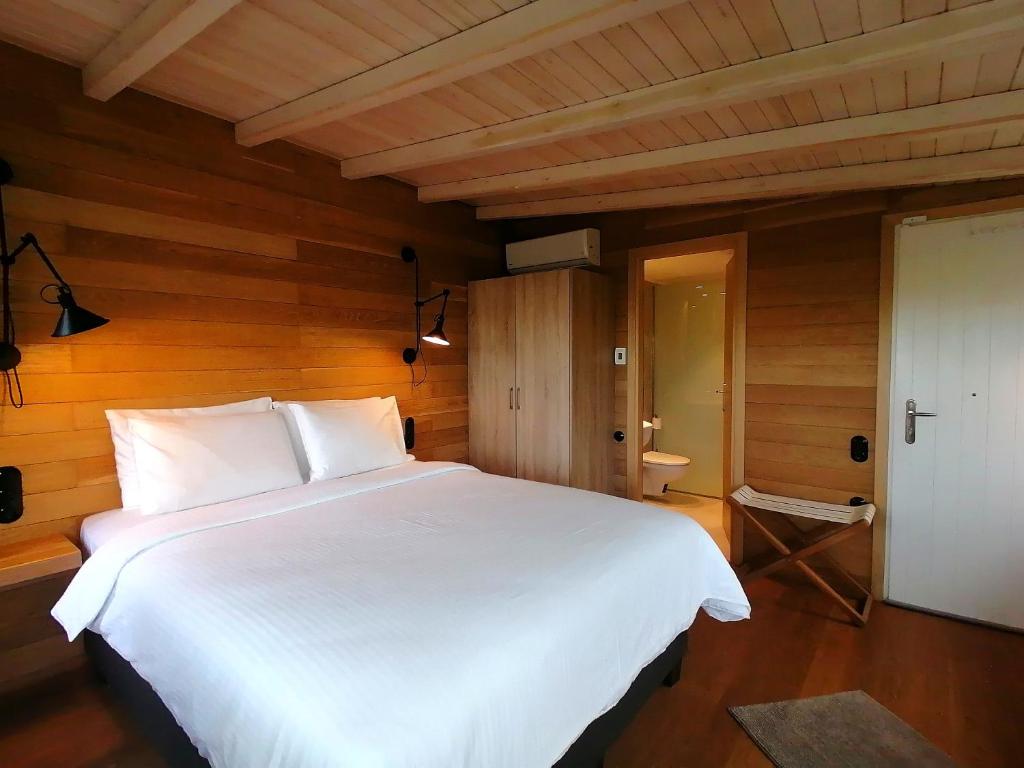 a large white bed in a room with wooden walls at K Lux Apartments in Paltsi Pilion