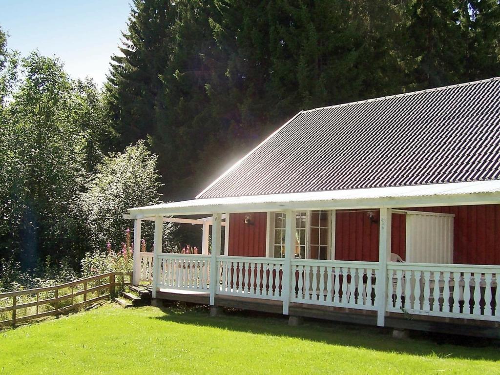a red house with a white porch and a fence at 6 person holiday home in TORSBY in Överbyn