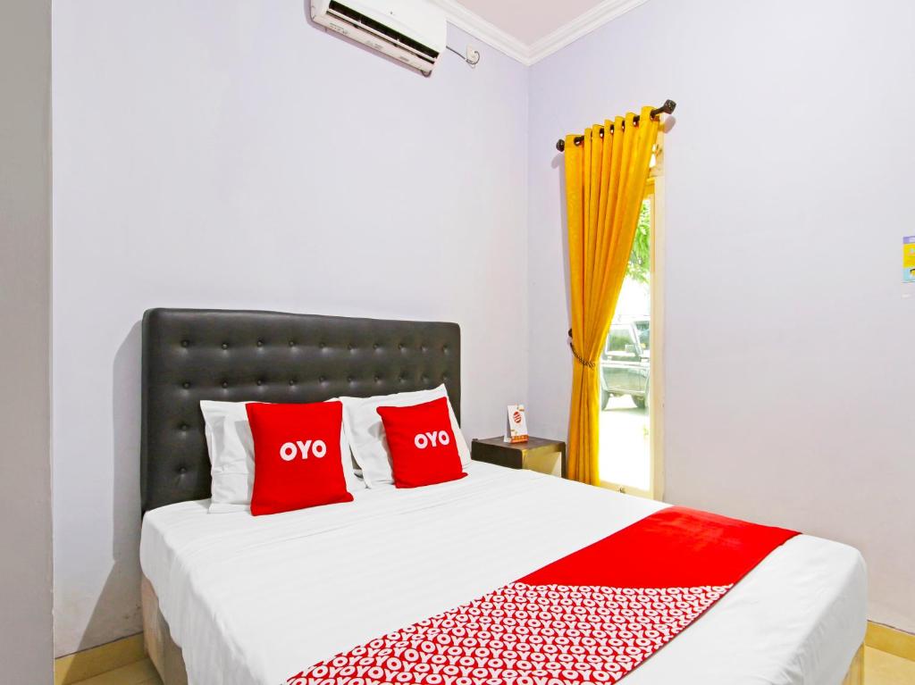 Un dormitorio con una cama con almohadas rojas y una ventana en Super OYO 91315 Homestay Al Maidah, en Sleman
