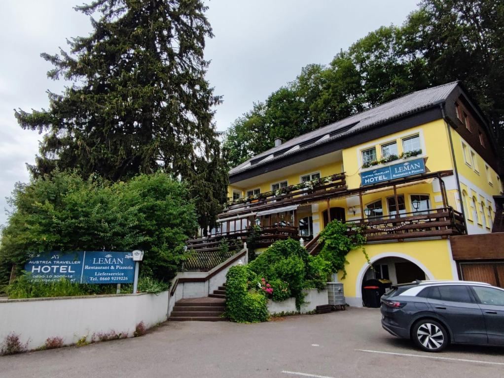 Lenzing的住宿－Austria Traveller Hotel Lenzing，一座黄色的建筑,前面有一辆汽车
