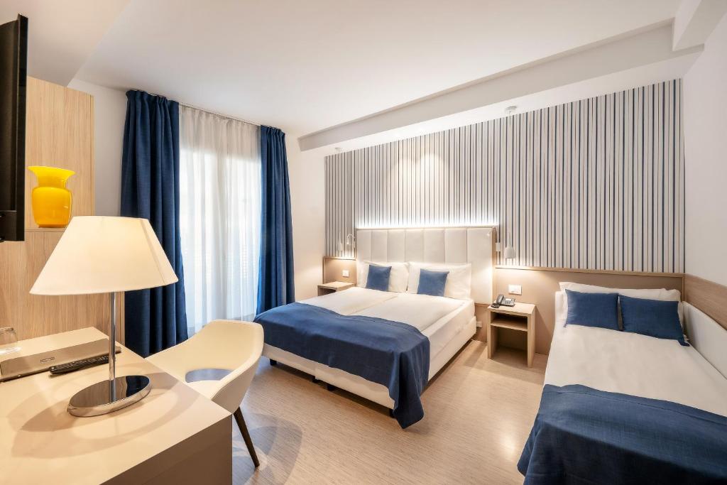 a hotel room with two beds and a desk at International Beach Hotel in Caorle