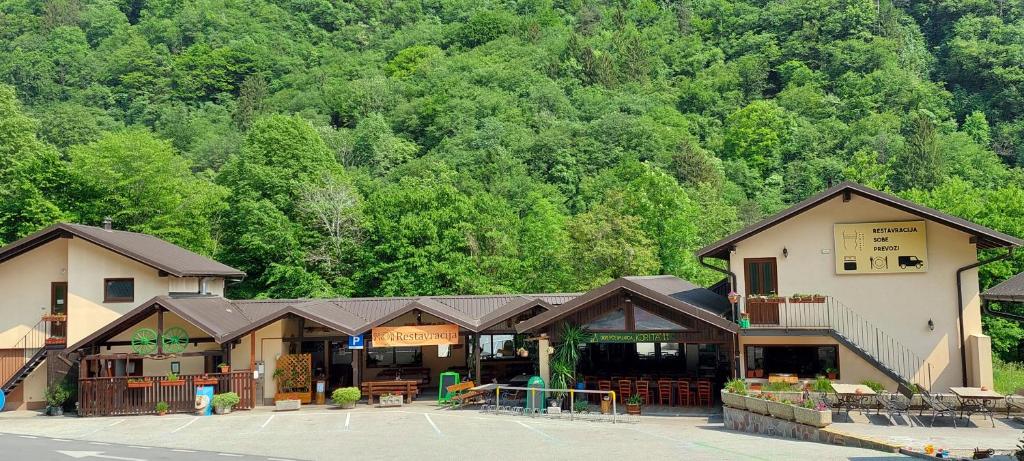 a building in a parking lot in front of a mountain at Rooms Tolminska korita in Tolmin