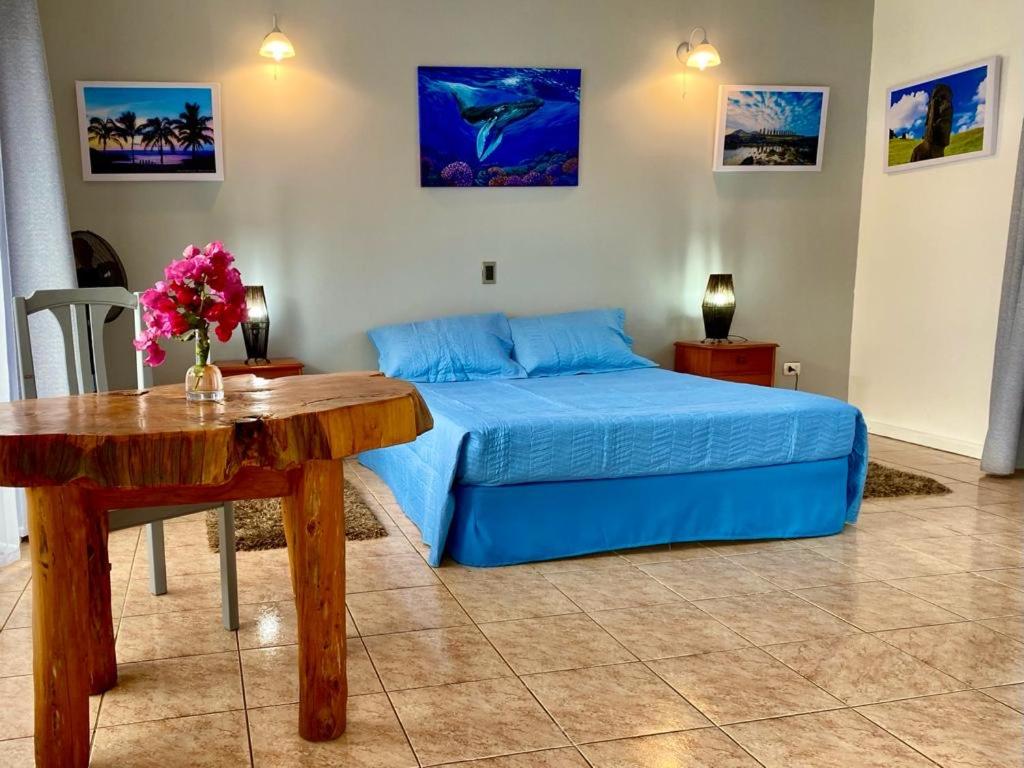 1 dormitorio con 1 cama y 1 mesa con 1 cama azul en Kahina Lodge, en Hanga Roa