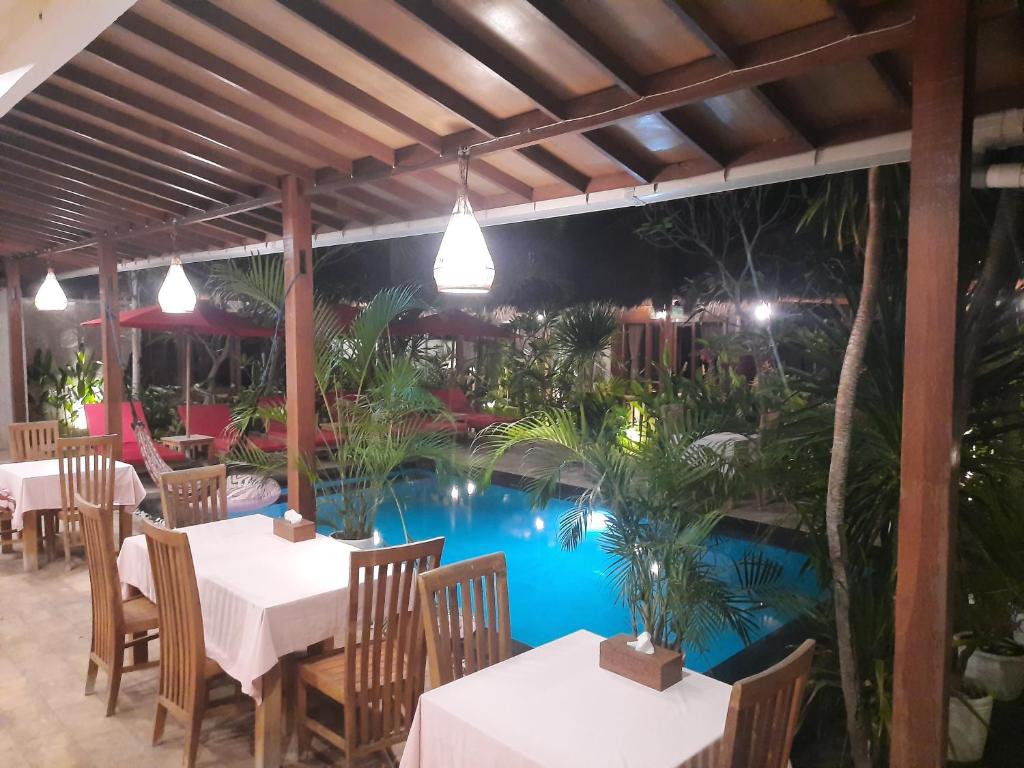 un restaurante con una piscina con mesas y sillas en Molah Gili Villa en Gili Air