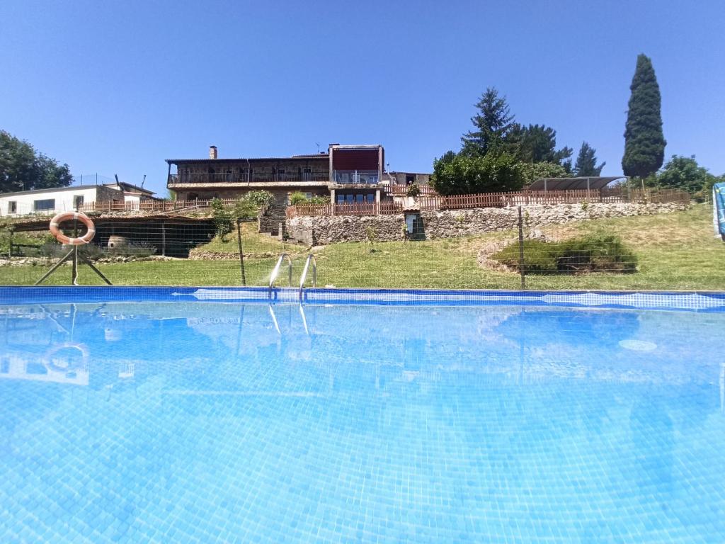 a large swimming pool with a house in the background at Casa dos Muros turismo rural y actividades en la Ribeira Sacra in Pantón