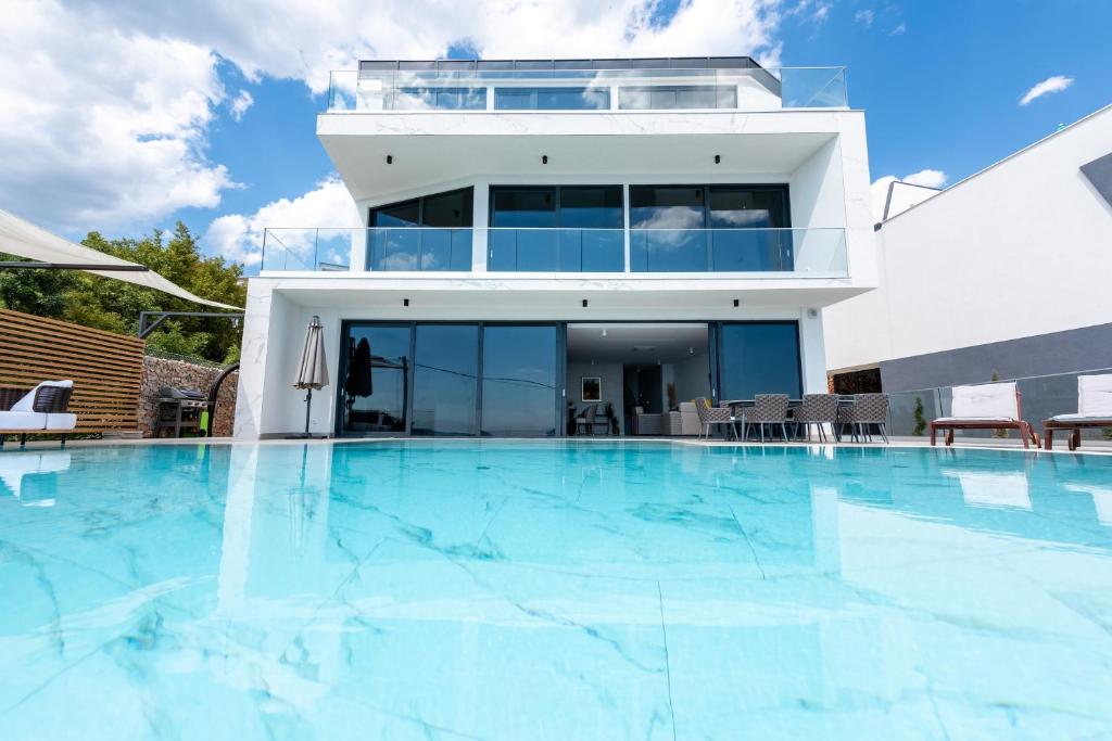 a large swimming pool in front of a house at Villa Laurynn with Roof Top Spa and Pool in Crikvenica