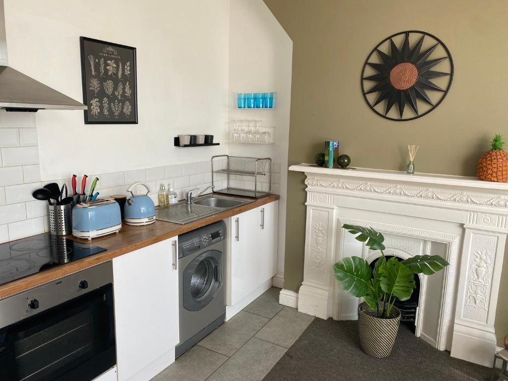 a kitchen with a washing machine and a fireplace at Walpole Bay Apartment in Cliftonville