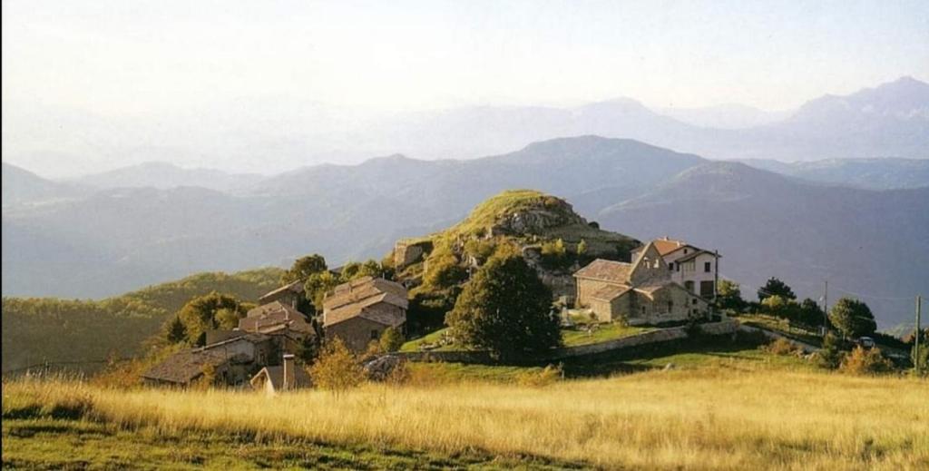 una casa en una colina con montañas en el fondo en Gite L'EISSAME, en Valavoire