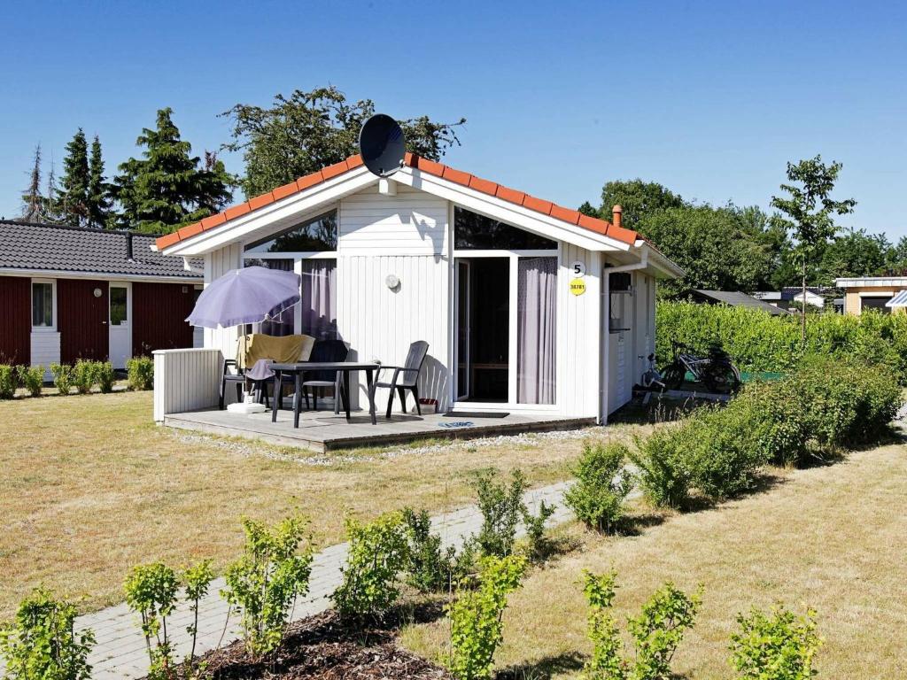 un cobertizo blanco con una mesa en un patio en 4 person holiday home in GROEMITZ, en Grömitz