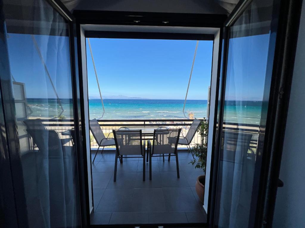 balcón con mesa, sillas y vistas al océano en MEDORA By the Sea Near Airport, en Artemida