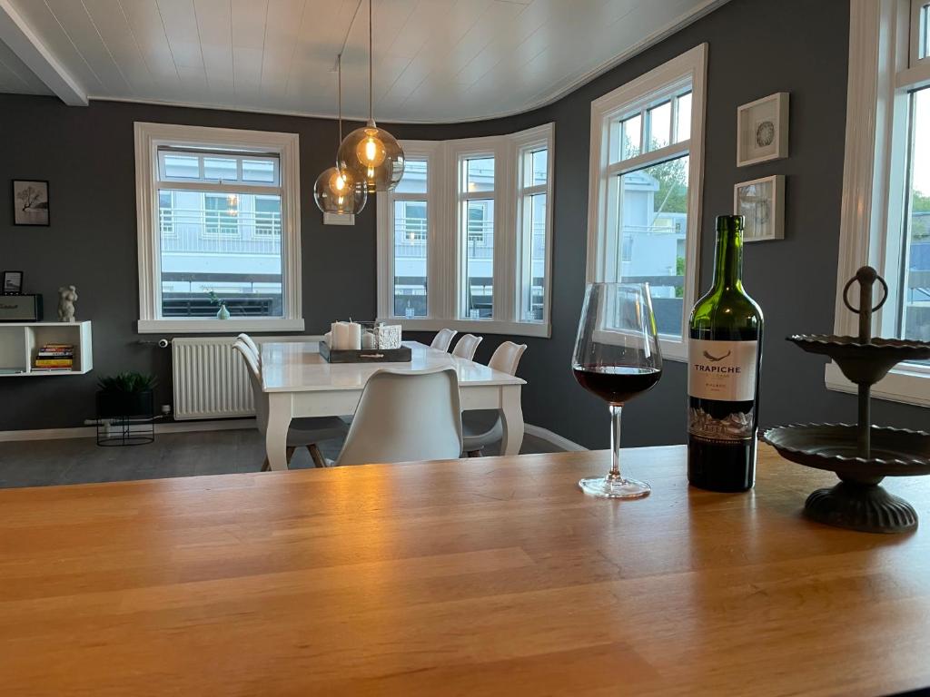 uma garrafa de vinho sentada numa mesa com um copo de vinho em Lovely Penthouse downtown with 3 bedrooms em Akureyri