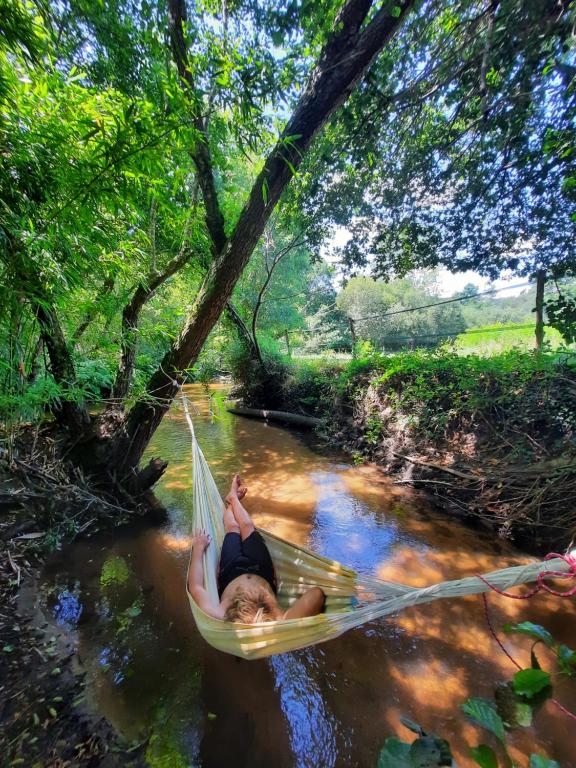 a woman is laying in a hammock in a river at Le tipi Arc-en-ciel au bord de la rivière in Mios