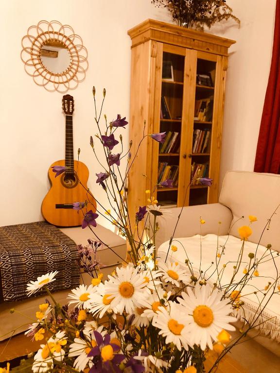 a room with a table with flowers and a guitar at Casa bunicilor in Ucea de Jos