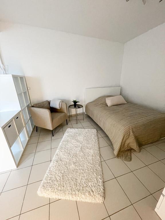 ein Schlafzimmer mit einem Bett, einem Stuhl und einem Teppich in der Unterkunft Schöne Einzimmerwohnung in Bad Nauheim