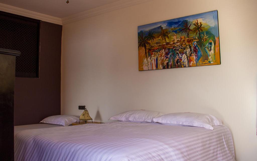 a bedroom with two beds and a painting on the wall at Peak House Imsouane in Imsouane