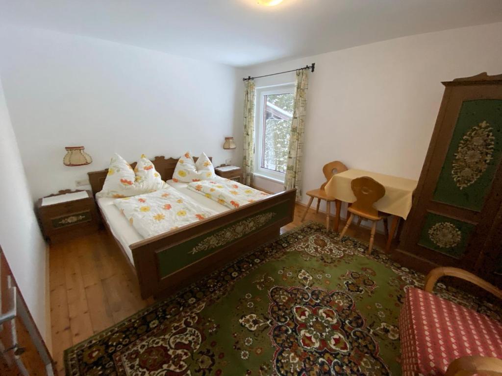 Schlafzimmer mit einem Bett, einem Tisch und einem Fenster in der Unterkunft Alpengasthof Wegscheid in Kelchsau