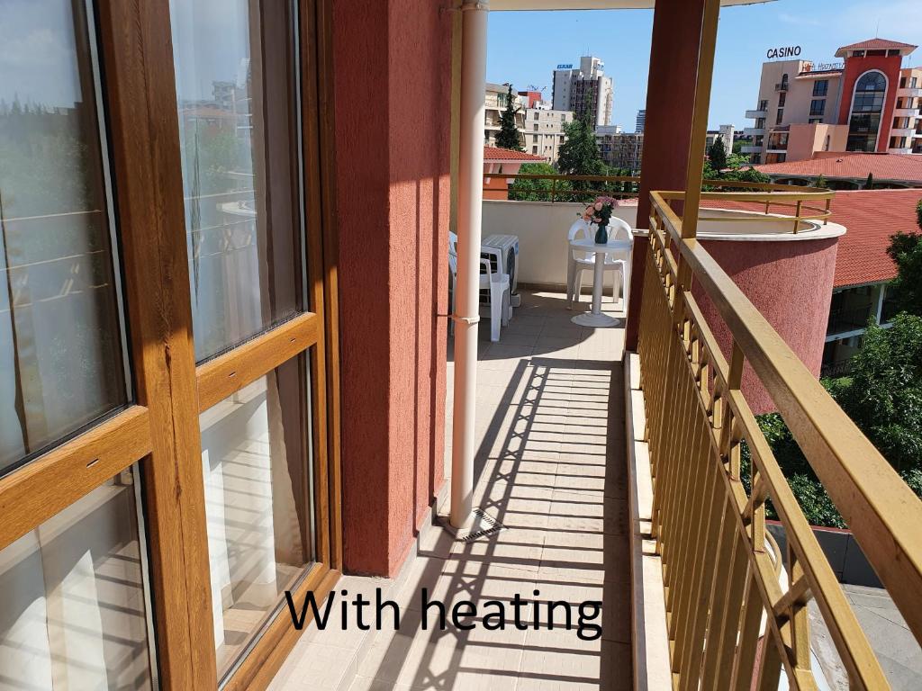 a balcony with a woman sitting at a table on a building at Apartment Ashton Hall - Sonnenstrand – Ost in Sunny Beach