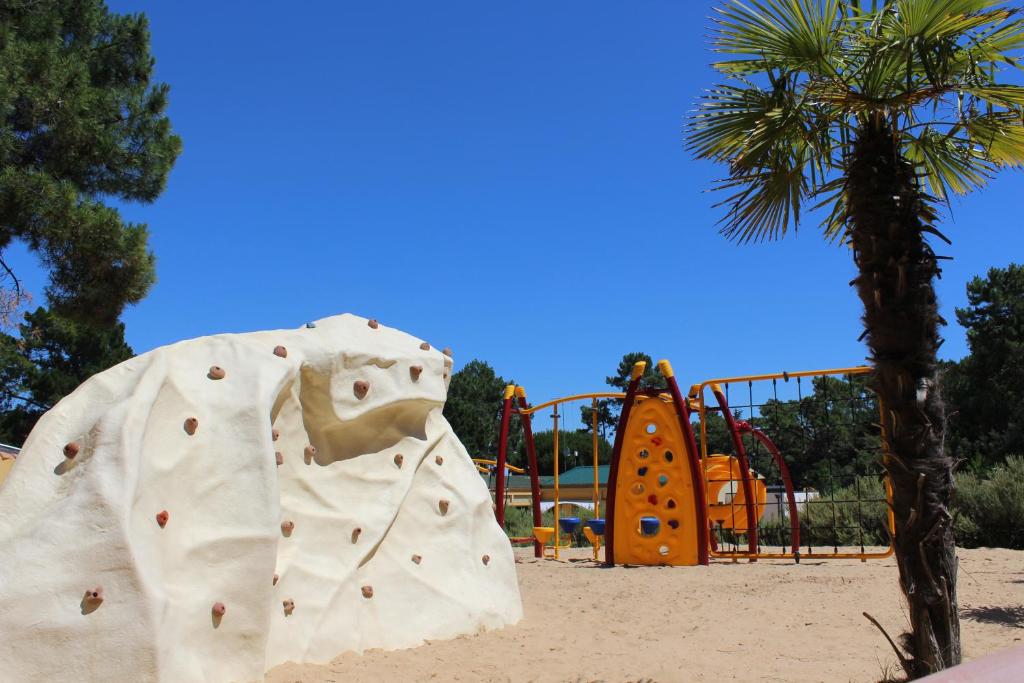 a playground with a white elephant statue next to a palm tree at Le Domaine des Pins in Saint-Hilaire-de-Riez