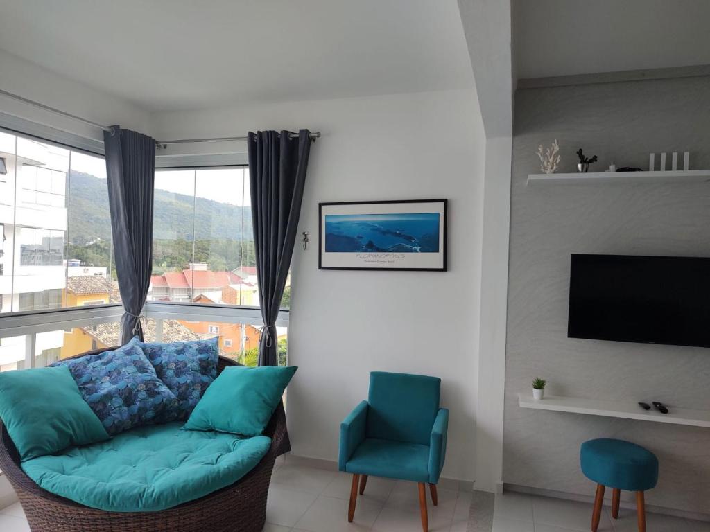 a living room with a couch and a tv at Apto Praia Palmas in Governador Celso Ramos