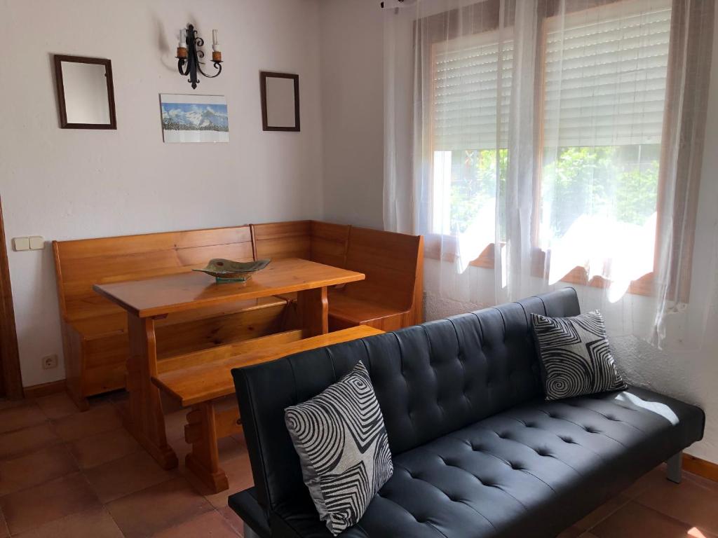 a living room with a black leather couch and a table at Casa Maria y Julián in Vilaller