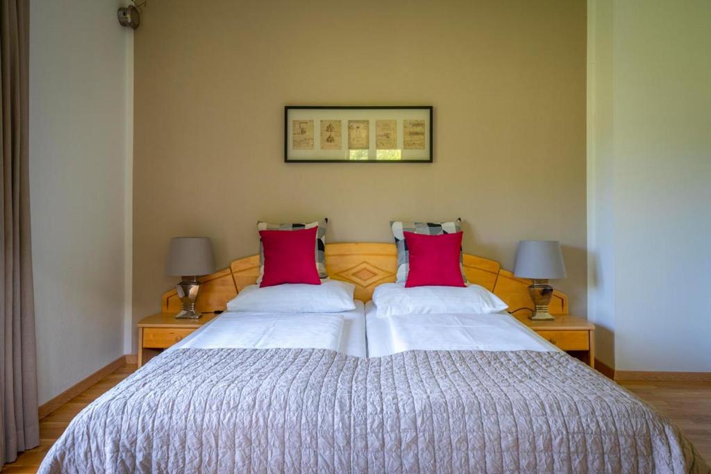 a bedroom with a large bed with two red pillows at Pension Strauß in Ossiach