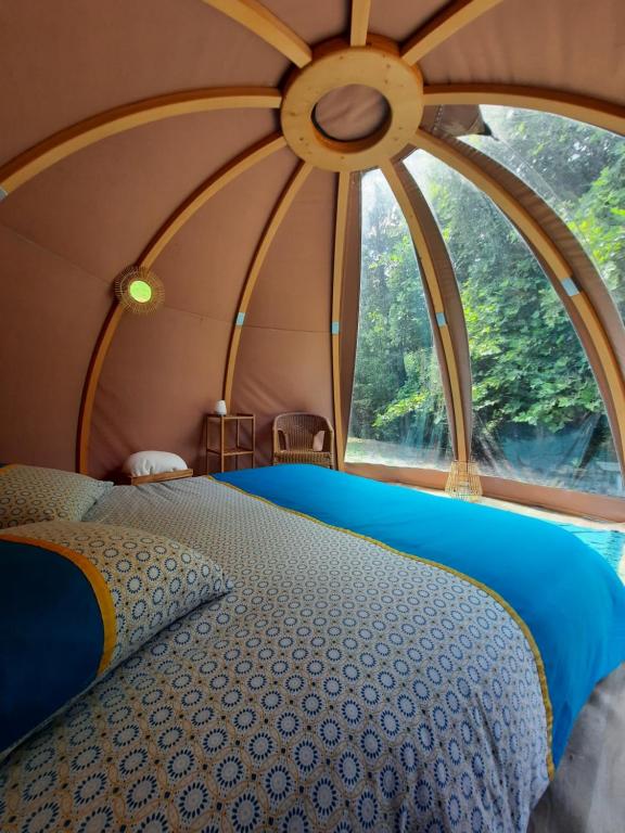 Bett in einem Zimmer mit einem großen Fenster in der Unterkunft La Wigwam Bleu du Domaine du Pas de l'âne in Mios