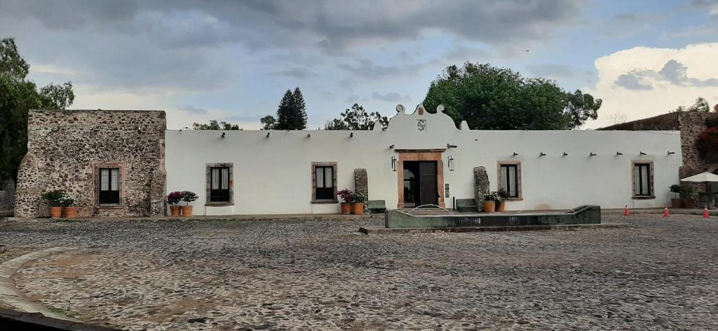 a white building sitting on top of a gravel yard at Hacienda El Salitre Hotel & Spa in Querétaro