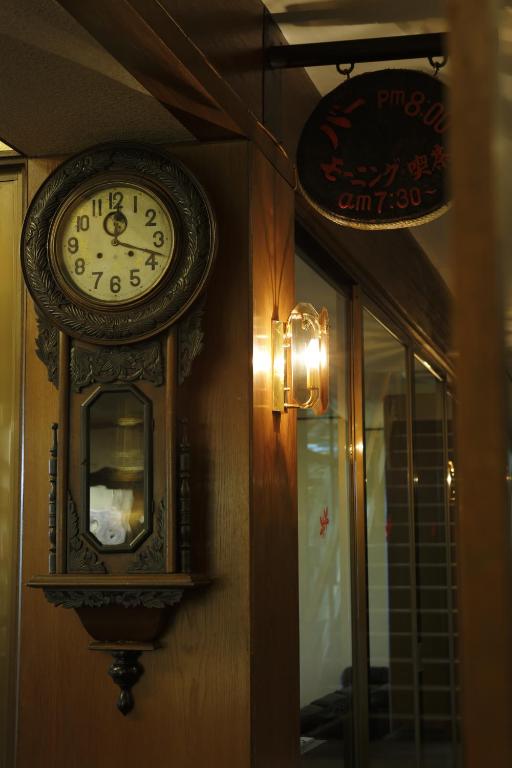 a clock hanging on a wall next to a window at Negiya Ryofukaku in Kobe
