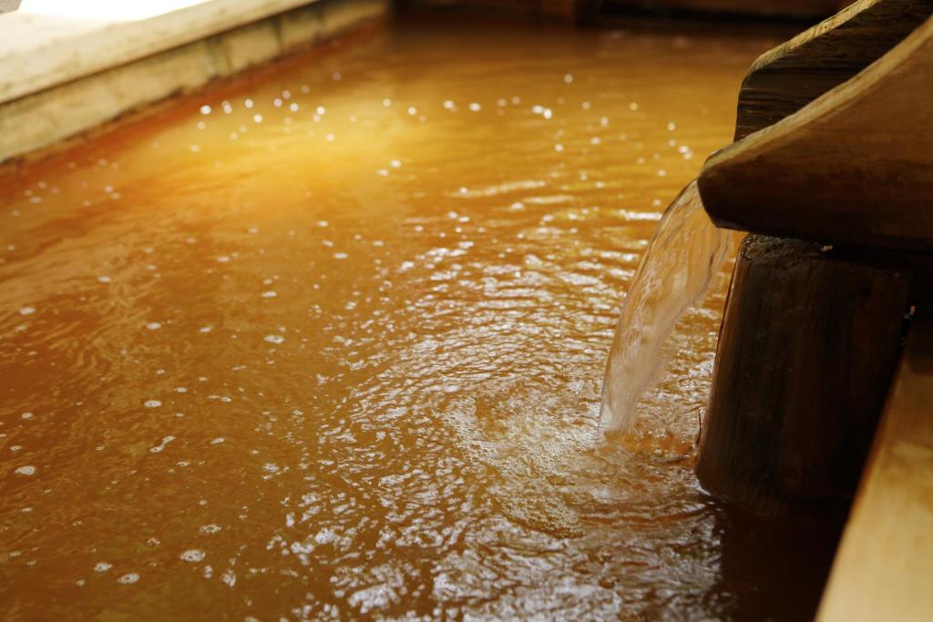 a stream of water pouring into a pool of water at Negiya Ryofukaku in Kobe