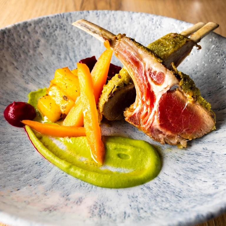 a plate of food with meat and vegetables and a pickle at Cool Šilo Appartement Resort in Šilo