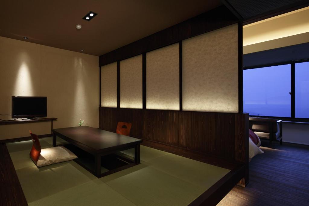 a living room with a table and a chair at Negiya Ryofukaku in Kobe