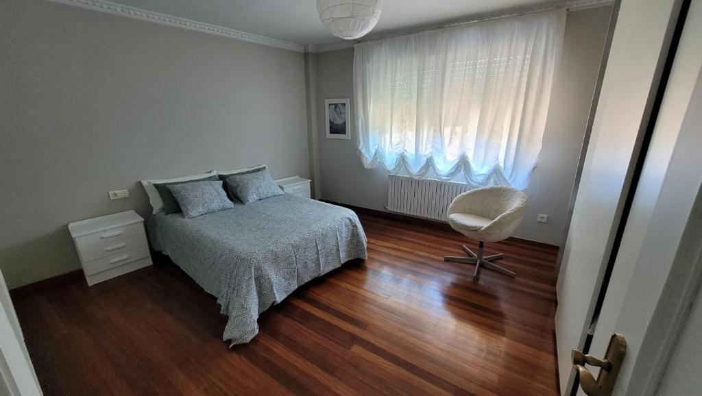 a bedroom with a bed and a chair and a window at Casa del Patio in Cangas de Morrazo