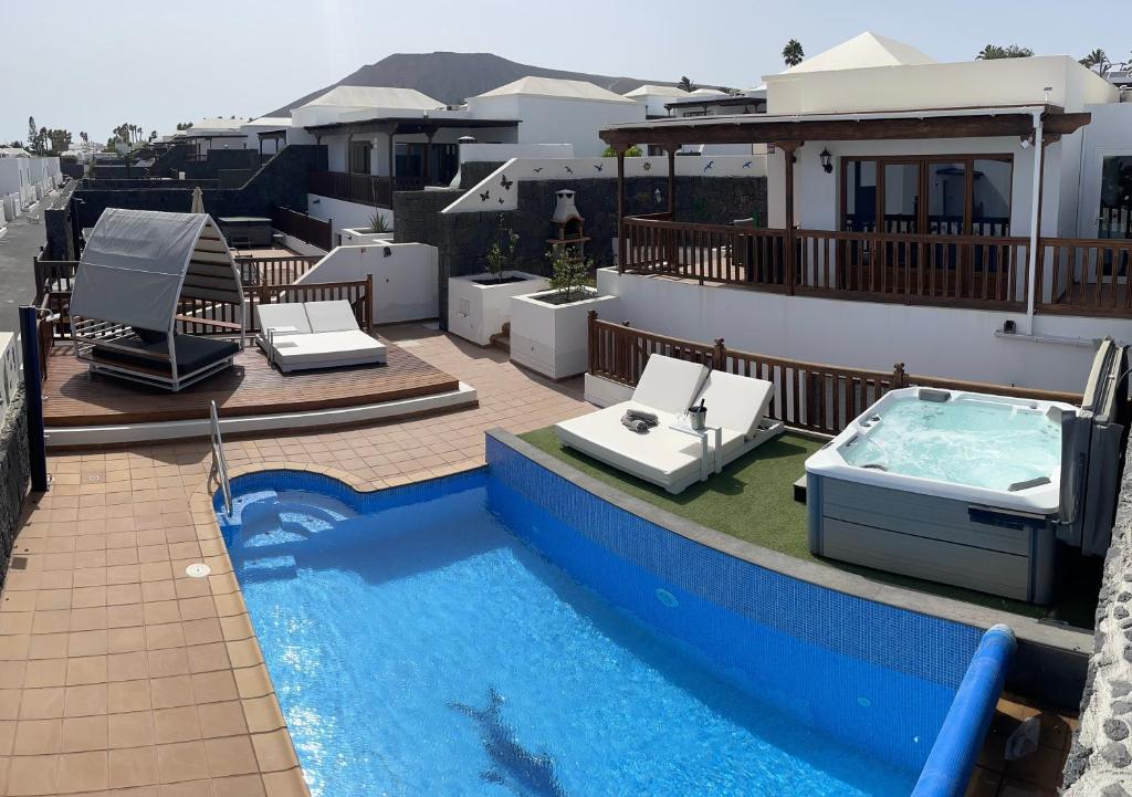 a large swimming pool next to a house with a hot tub at Villa 64, Vista Lobos, private heated pool x jacuzzi, Playa Blanca in Playa Blanca