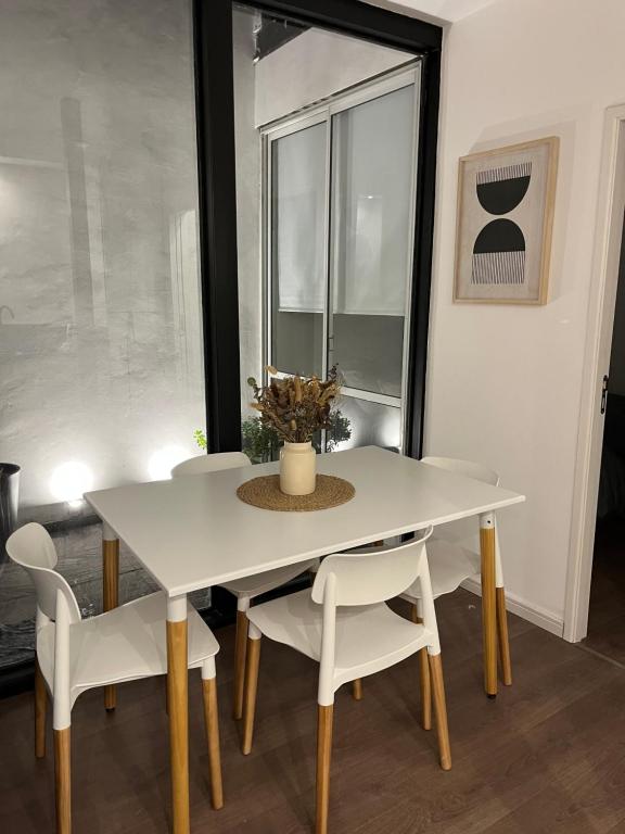 uma mesa de jantar com cadeiras brancas e uma janela em PATAGONIA FLAT em Esquel