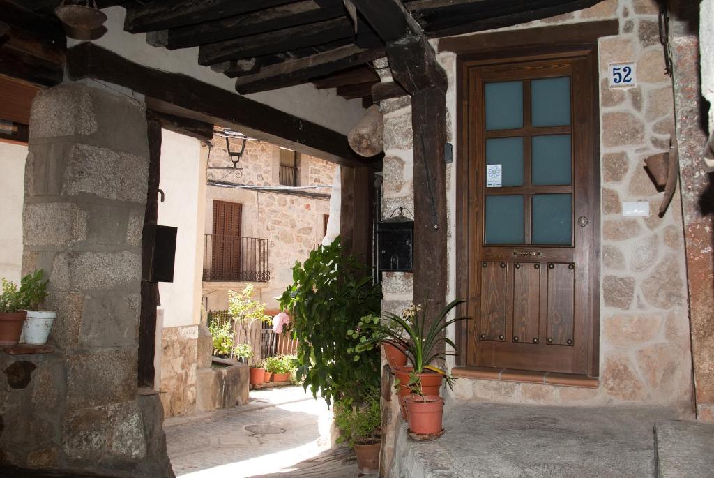 a stone house with a wooden door and potted plants at LA CASITA DEL PORTAL in Pedro Bernardo