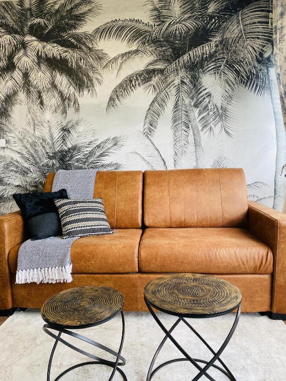 un canapé marron dans un salon avec deux tables dans l'établissement L'instant présent - Petite vue mer, à Villers-sur-Mer