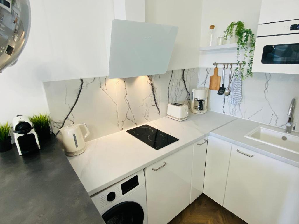 a white kitchen with a sink and a stove at L'instant présent - Petite vue mer in Villers-sur-Mer
