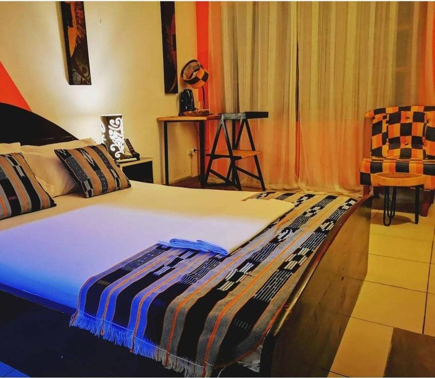 1 dormitorio con 1 cama y 1 silla en La Maison de Canelya, en Cotonou